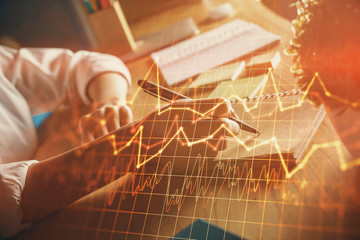 Financial forex charts displayed on woman's hand taking notes background. Concept of research....