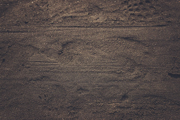 Black sand texture on the beach with some footprint on surface - process in space tone