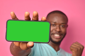 excited young black man showing the screen of his mobile smartphone and celebrating