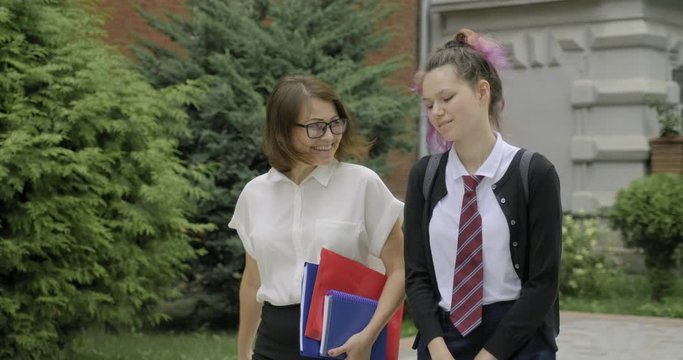 Woman teacher and girl teenager high school student walking