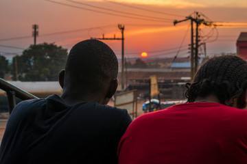 young black man and lady sitting together outside having a conversation and watching the evening...