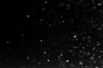Falling  snow at night. Bokeh lights on black background, flying snowflakes in the air. Overlay...
