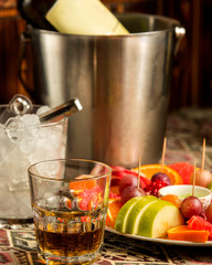 glass of whiskey and a plate of fruit