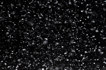 Falling  snow at night. Bokeh lights on black background, flying snowflakes in the air. Overlay...