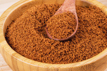Bowl full of dark brown sugar on a wooden background