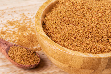 Bowl full of dark light sugar on a wooden background