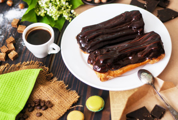 Fresh homemade eclairs with chocolate on the kitchen table. French pastries.
