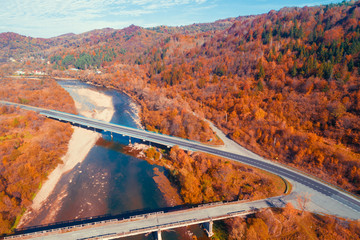 Panoramic view of a mountain valley with river, highway, and bridges in autumn. View from above