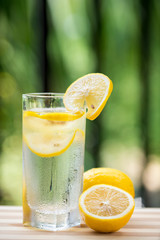 A glass of lemonade and cut lemon on a red table
