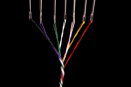 7 steel sewing needles threaded with various colored threads which are twisted into a simble thick thread.  Room for copy left and right.