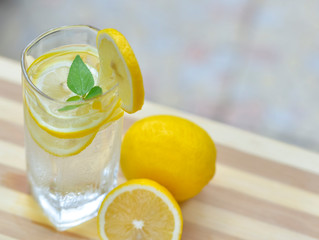 A glass of lemonade and cut lemon on a red table