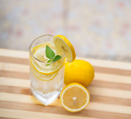 A glass of lemonade and cut lemon on a red table