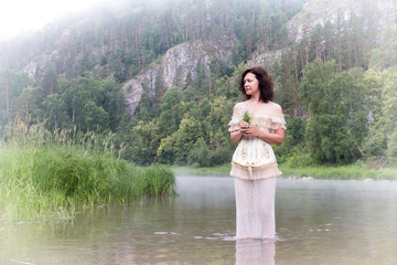 Beautiful young woman on the river in the morning fog