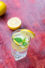 A glass of lemonade and cut lemon on a red table