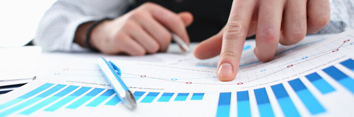 Male arm hold silver pen and point finger in financial graph