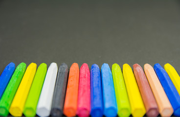 set of random crayon colors with crayon nibs in focus on a black chart background
