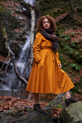 Woman in yellow coat by a waterfall