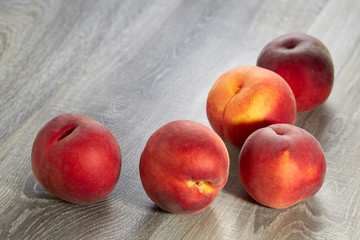 Five ripe peaches lie on the wood table. Natural fruit.