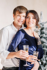 Man and woman withglasses champagne near the New Year's table for Christmas. A man hugs a woman. Couple celebrating New Years Eve 2019.