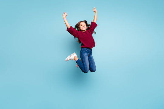 Full length body size photo of positive cheerful curly girl jumping up wearing jeans denim smiling toothily isolated vivid blue color background