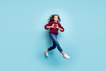 Full length body size photo of cheerful positive girlfriend jumping running showing heart sign wearing jeans denim burgundy sweater isolated blue vivid color background