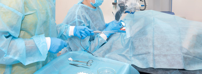 Nurse giving a tool to a doctor during surgery. Hands of doctors during hospital surgery. Ear...