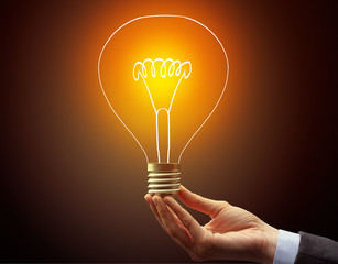 Hand holding light bulb on dark background, new idea concept
