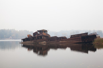 Old sunken ship in water in a foggy day