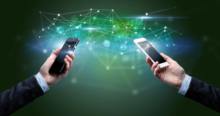 Close up of two hands holding smartphones and sharing business data