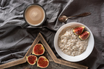Healthy breakfast in bed. Coffee, porridge with figs, on a rustic wooden board. Clean food, alkaline diet, 