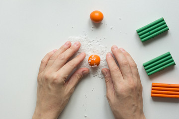 Small orange ball made from polymer clay on white background with sea salt before making dents on orange fruit