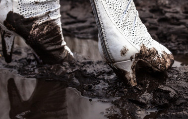 Dirty white high-heel shoes in the mud