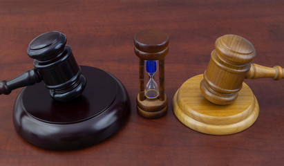 Different court decisions and time concept with two gavels on table with hourglass