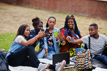 Group of five african college students spending time together on campus at university yard. Black afro friends making with mobile phones. Education theme.
