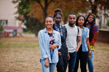 Row of group five african college students spending time together on campus at university yard....