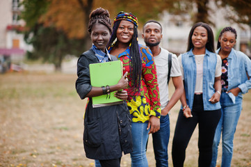 Row of group five african college students spending time together on campus at university yard. Black afro friends studying. Education theme. - obrazy, fototapety, plakaty