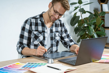 Young adult worker working with graphic tablet in office