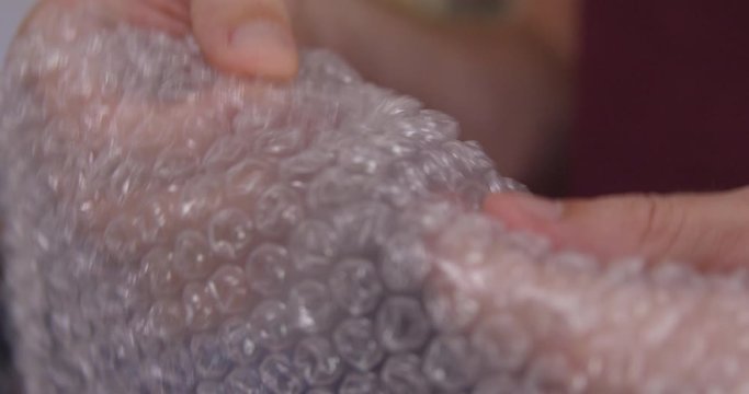 Close Up - Packing bubblewrap is popped one bubble at a time - shot on RED