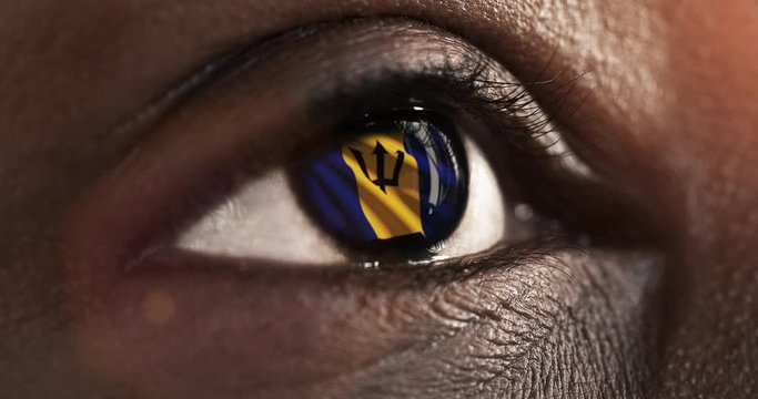 Woman black eye in close up with the flag of Barbados in iris with wind motion. video concept