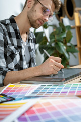Young adult retoucher working with graphic tablet in office