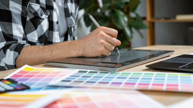 Young adult illustrator working with graphic tablet in office