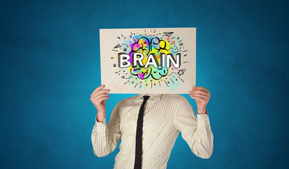 Young person holding white paper in front of her head with colorful brain concept