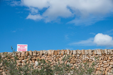 Mur en pierres sèches et panneau de propriété privée, proche de la plage de Macarella, une des plus belles plages de Minorque, îles Baléares.