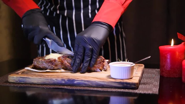 Rib eye steak at the christmas table. A waiter in gloves cuts a juicy steak. Restaurant chef slicing medium rare beef steak.