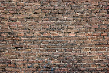 Very old brownish brick wall with some darker spots, background texture