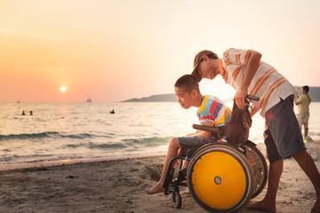 Asian special child on wheelchair is happily on the beach with father,Dad and son spend holiday to...