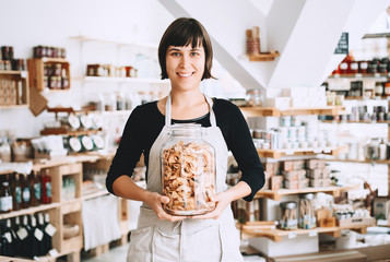 Owner or seller with glass jar of groceries in zero waste shop.