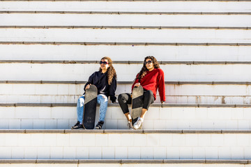 Two happy teen skaters resting on the stairs