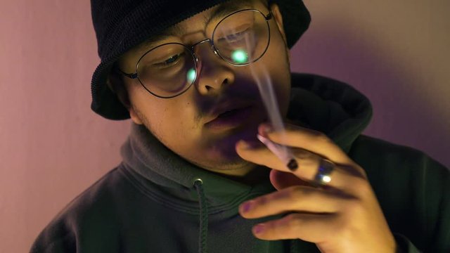 Young Male Lighting a Cannabis Joint and Taking puffs afterwards.