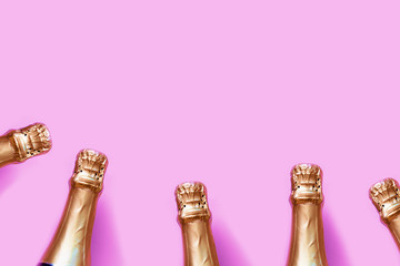 Gold champagne bottles on a pastel pink background with bokeh lights - Christmas / New Year / Bachelorette party festive backdrop
